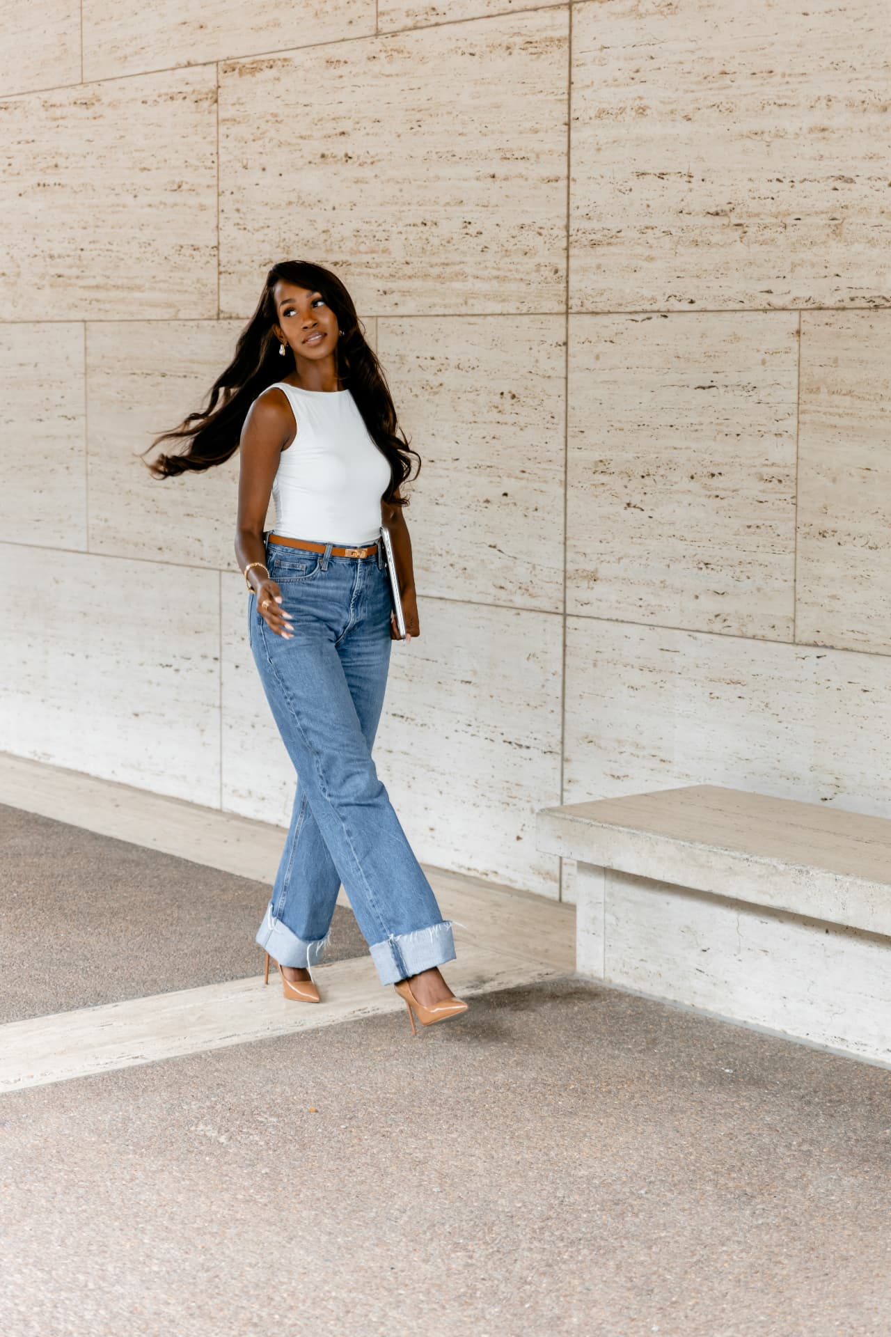 Courtney Washington walking beside a limestone wall with her laptop