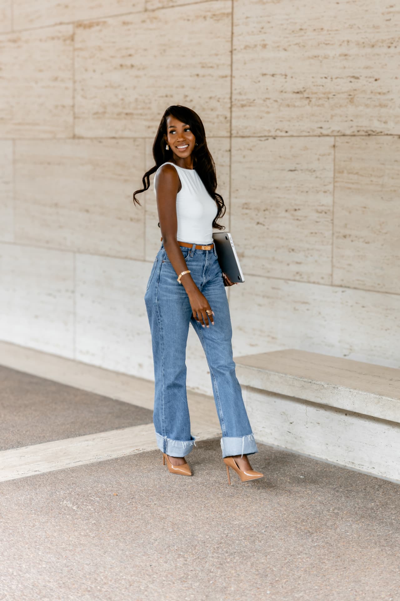 Courtney Washington smiling and holding her laptop beside a limestone wall