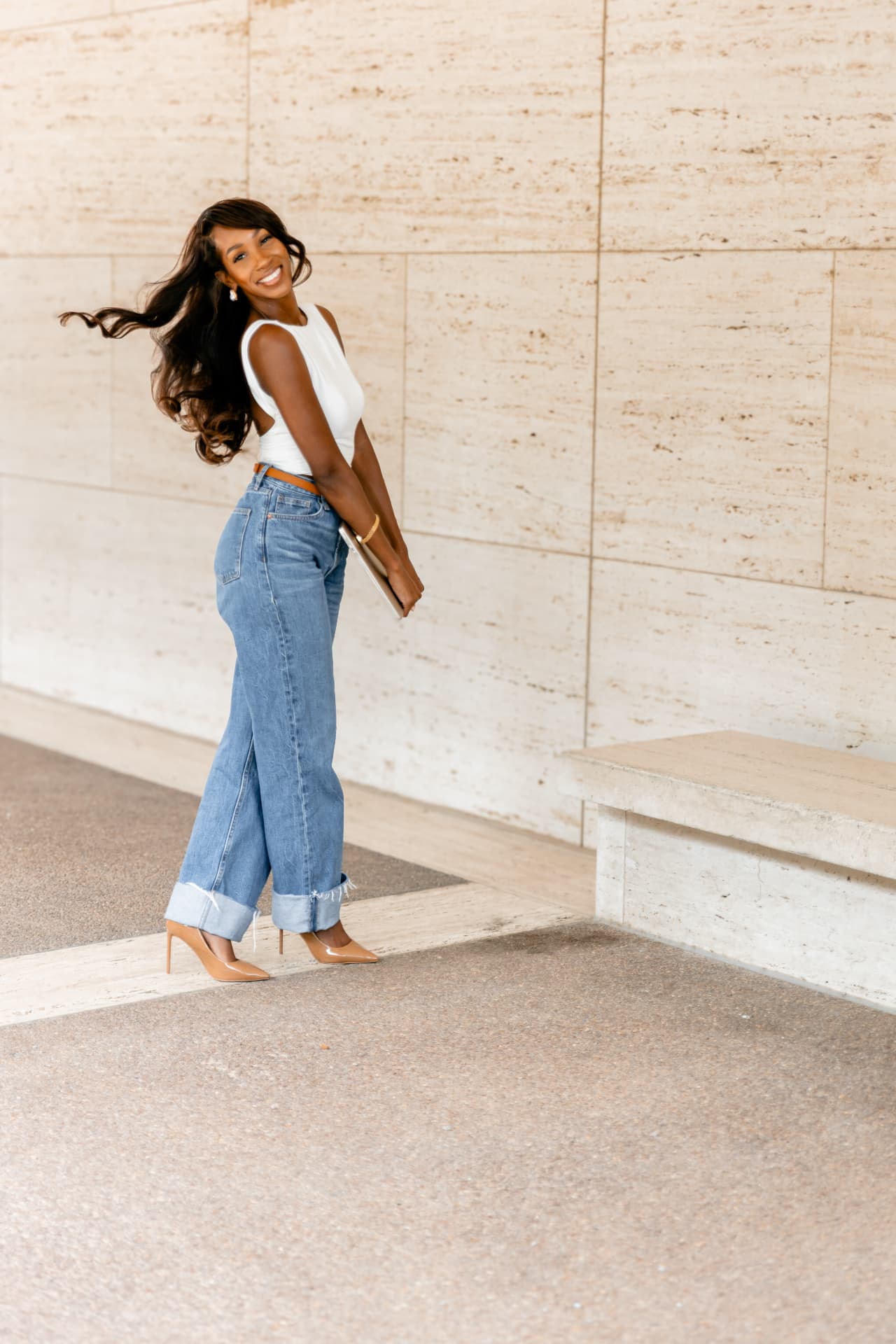 Courtney Washington smiling in a white blouse and jeans beside a limestone wall